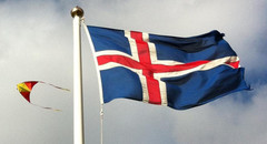 picture of an Icelandic flag. A kite taking aerial photographs in the background.